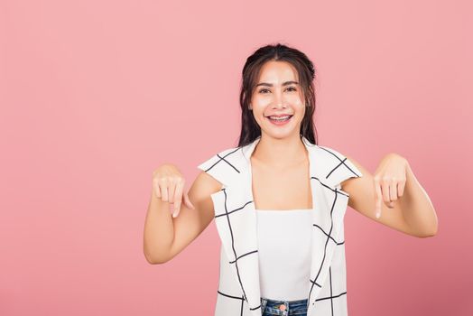 Portrait Asian beautiful young woman unhappy, negative gesture showing finger thumbs down or dislike sign, studio shot isolated on pink background, Thai female rejection unlike with copy space