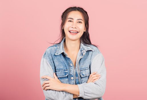 Asian happy portrait beautiful cute young woman wear denim standing her smile confidence with crossed arms isolated, studio shot on pink background and copy space, Thai female looking to camera