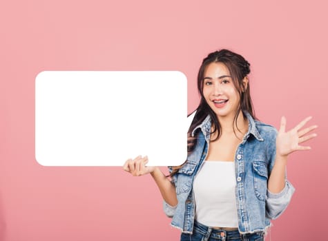Happy Asian beautiful young woman smiling excited wear denims holding empty speech bubble sign, Portrait female posing show up for your idea looking at camera, studio shot isolated on pink background
