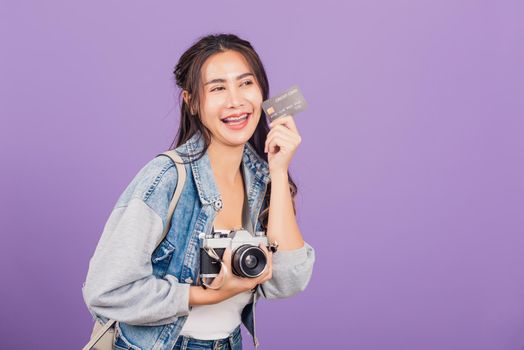 Happy Asian portrait beautiful young woman excited smiling photographer holding debit credit card bank and retro vintage photo camera ready travel isolated on purple background, tourism and vacation