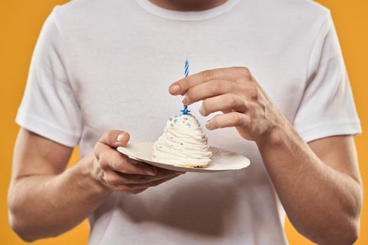 A man with a birthday cake in his hands on a yellow background birthday dessert. High quality photo