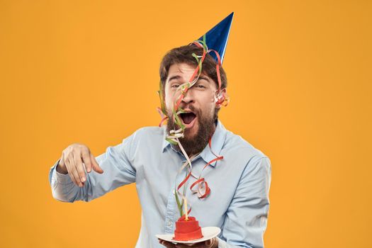 Guy with a cake in a plate on a yellow background holidays candle cropped view. High quality photo