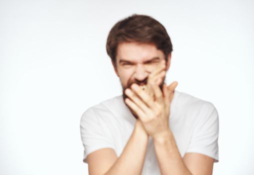 Emotional man with a beard holds his hands near his face on a light background cropped view. High quality photo