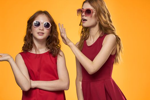 Two sisters and fun sunglasses fashion Friendship yellow background family. High quality photo