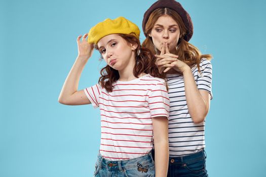Fashion sisters in hats fun lifestyle blue background studio. High quality photo