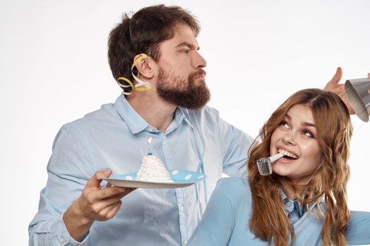 energetic man and woman with a cake and in hats celebrate a birthday on a light background. High quality photo
