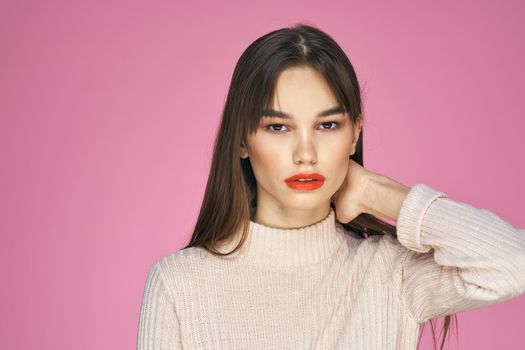 Pretty brunette in a white sweater red lips attractive look pink background. High quality photo