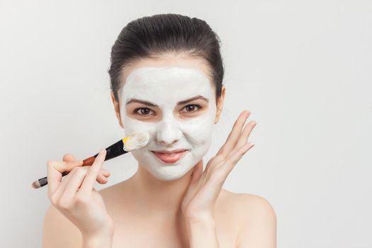 pretty brunette with makeup brush in hands skin care mask rejuvenation. High quality photo