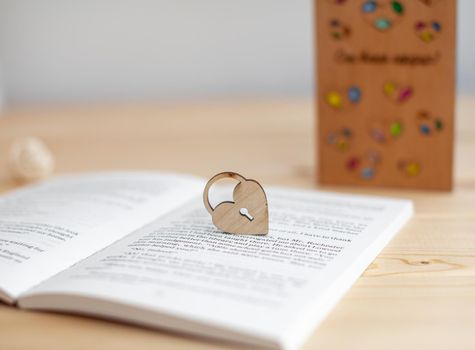 A wooden heart with a keyhole rests on an open book. There is a place for the text.