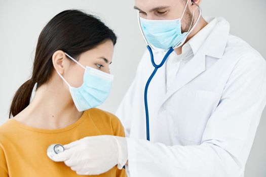 professional doctor in a medical gown examines a female patient in a blue mask. High quality photo