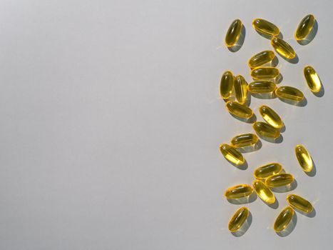 Vitamin D3, Omega or Evening Primula Oil gel capsules on neutral gray background. Top view or flat lay yellow liquid capsules with nutritional supplement oil. Copy space for text.