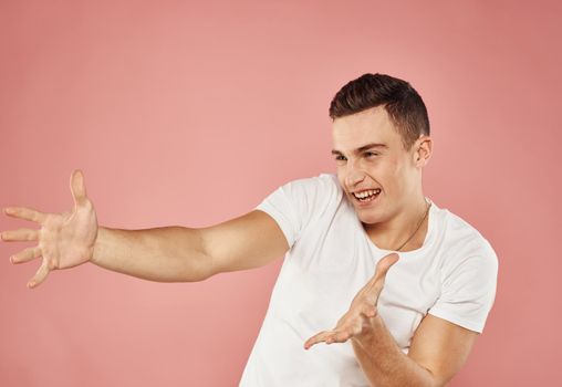 emotional man in white t-shirt gesturing with hands cropped view pink background. High quality photo