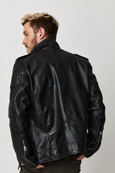 stylish guy in a leather jacket looks to the side back view. High quality photo