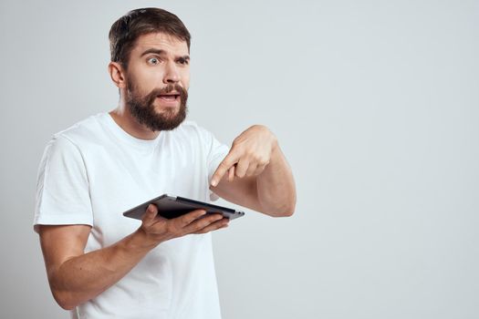 A bearded man in a white t-shirt a tablet in the hands of a professional manager communication technology. High quality photo