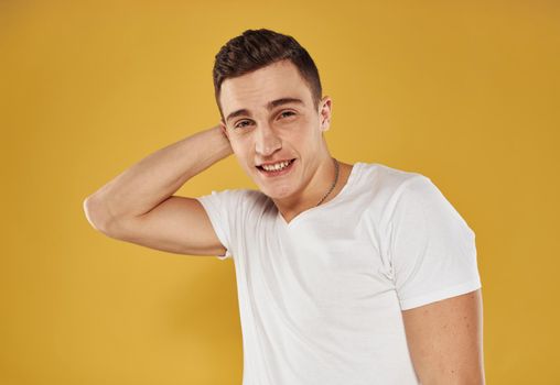 Portrait of a handsome guy in a white t-shirt on a yellow background cropped view. High quality photo