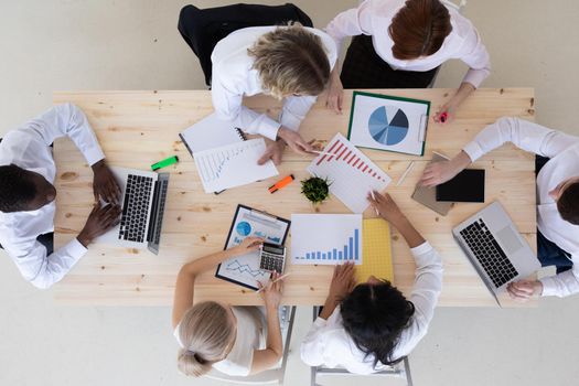 Business people brainstorming at office desk analyzing financial reports and pointing out financial data on a sheet, top view