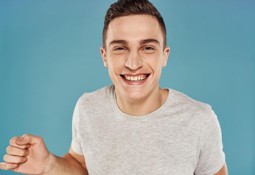 Cheerful handsome man white t-shirt closeup emotions blue background. High quality photo