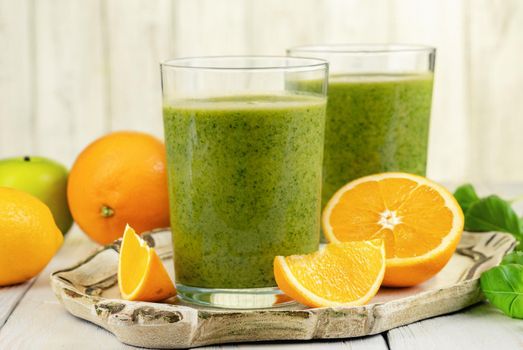 Healthy green smoothie with spinach, mango, orange,lime, apple,citrone in glass jars.