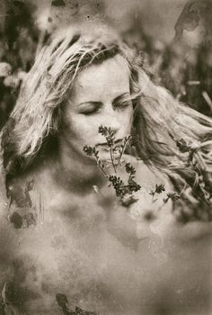 Artistic portrait of freckled woman on natural background. Young woman enjoying nature among the flowers and grass. Old film stylization. Grain added