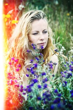 Artistic portrait of freckled woman on natural background. Young woman enjoying nature among the flowers and grass. Old film stylization