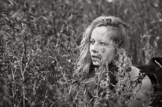 Black and white artistic portrait of freckled woman on natural background. Young woman enjoying nature among the flowers and grass. Close up summer portrait 
