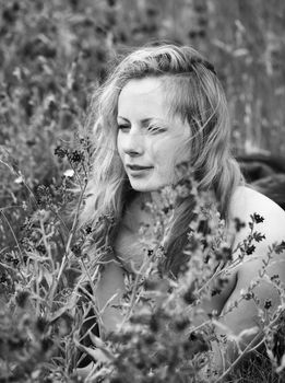 Black and white portrait of freckled woman on natural background. Young woman enjoying nature among the flowers and grass. Close up summer portrait 