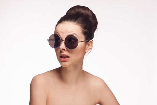 pretty brunette naked shoulders sunglasses clear skin light background. High quality photo