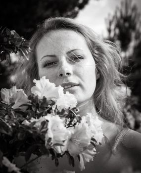 Beauty and youth concept. Portrait of a beautiful blonde young woman among the flowers of azalea