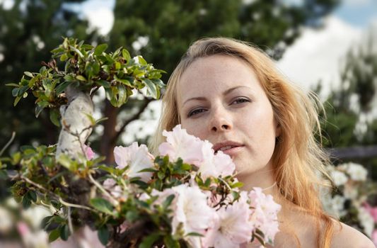 Beauty and youth concept. Portrait of a beautiful blonde young woman among the flowers of azalea