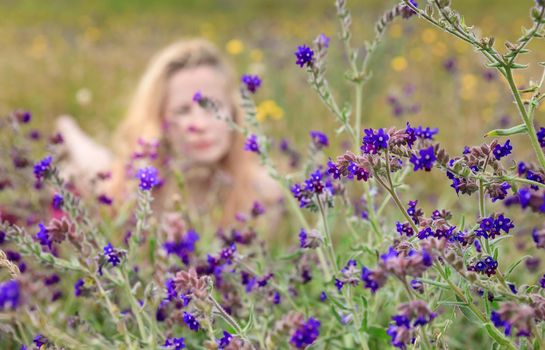 Artistic portrait of freckled woman on natural background. Young woman enjoying nature among the flowers and grass. Close up summer portrait 