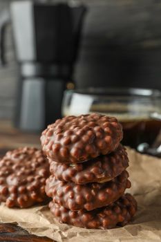 Stack of chocolate cookies and cup of coffee on wooden table against dark background, space for text
