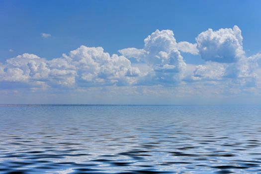 Seascape with a large pebble beach and blue sea to the horizon.
