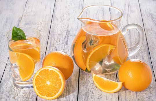 Healthy orange detox with fresh orange and lime, in glass on wooden Background.