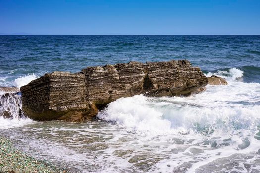 Seascape with a rock in the waves. Glass beach in Vladivostok.