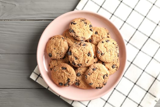 Plate with chocolate chip cookies and space for text on wooden table, top view