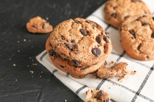 Tasty chocolate chip cookies on napkin and wooden background