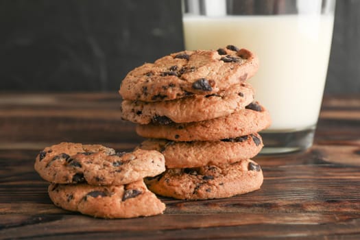 Tasty chocolate chip cookies and glass of milk on wooden table. Space for text