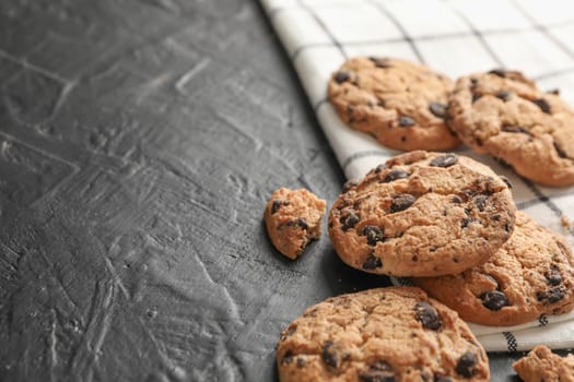 Tasty chocolate chip cookies on napkin and wooden background. Space for text