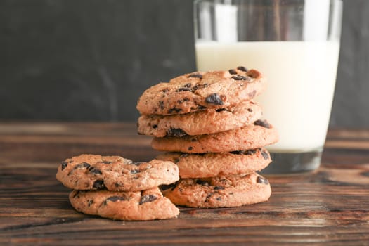 Tasty chocolate chip cookies and glass of milk on wooden table. Space for text