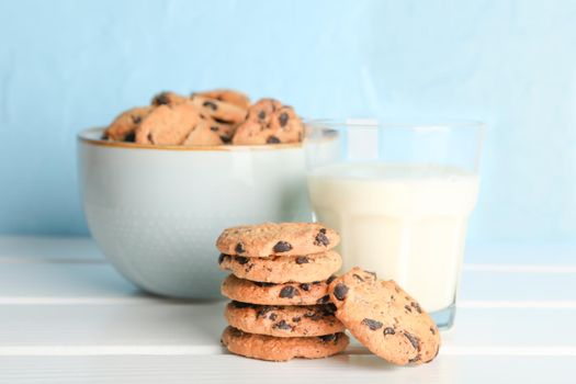 Tasty chocolate chip cookies and glass of milk on wooden table