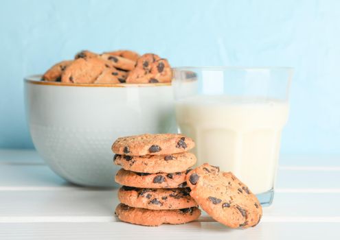 Tasty chocolate chip cookies and glass of milk on wooden table