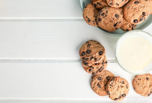 Tasty chocolate chip cookies and glass of milk on wooden table. Space for text