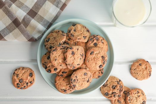 Tasty chocolate chip cookies and glass of milk on wooden table