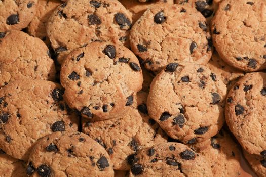 Tasty chocolate chip cookies as background, top view