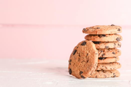 Stack of tasty chocolate chip cookies on wooden background. Space for text