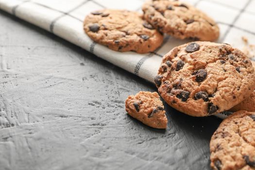 Tasty chocolate chip cookies on napkin and wooden background. Space for text