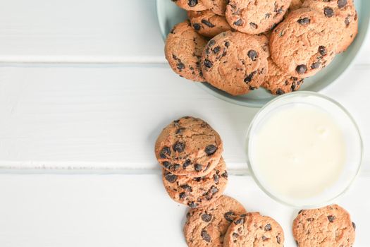 Tasty chocolate chip cookies and glass of milk on wooden table. Space for text