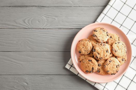 Plate with chocolate chip cookies and space for text on wooden table, top view