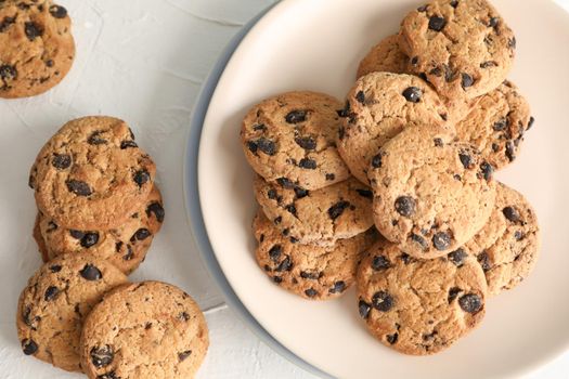 Plate with tasty chocolate chip cookies  on gray background, top view