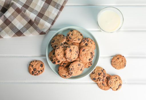 Tasty chocolate chip cookies and glass of milk on wooden table